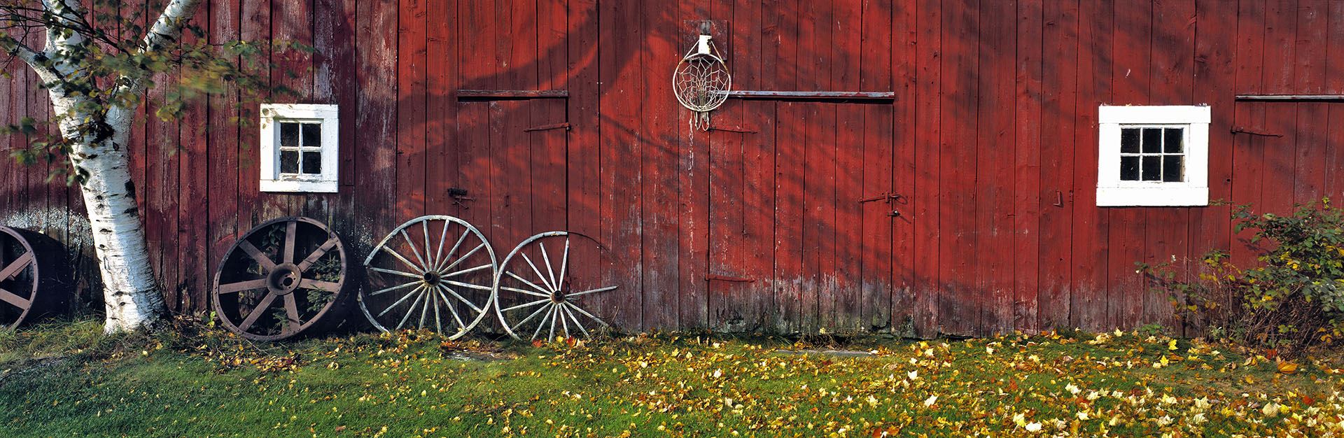 Wooden wagon wheels leaning against a red barn